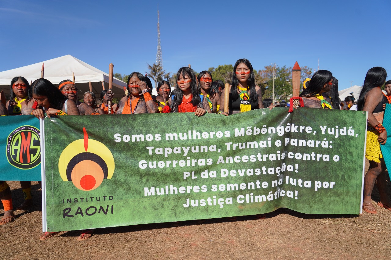 Kayapó delegation carrying banners and wearing traditional beadwork in Brasília